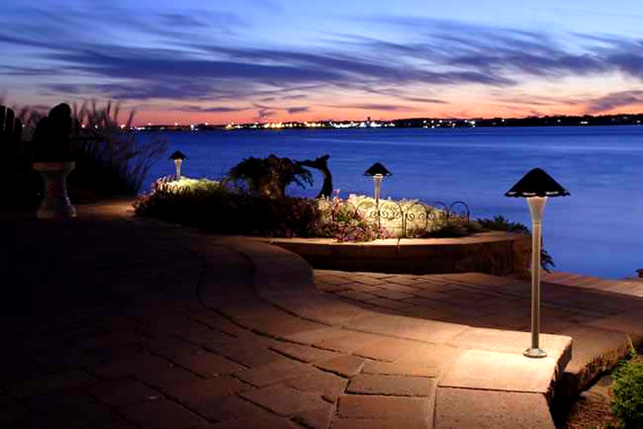 Coastal patio at dusk with sculptural path lighting over the water